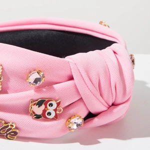 Detailed macro view of pink fabric knotted headband with rhinestone and owl charm