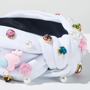 Detail of white fabric headband featuring multi-color rhinestones, pearls and wing heart