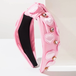 Close-up of pink fabric headband with lace heart patches and sparkling rhinestones