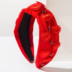 Detail of red fabric headband with sparkling heart patches and rhinestone accents