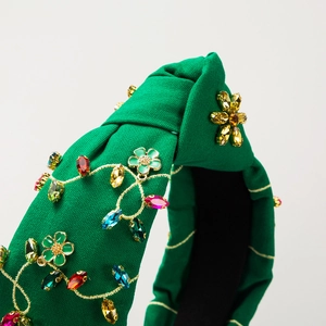 Close-up of green knotted headband featuring multicolored rhinestones and floral charms