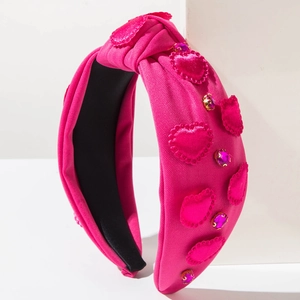 Macro detail of fuchsia knotted headband with 3D fabric hearts and pink rhinestones