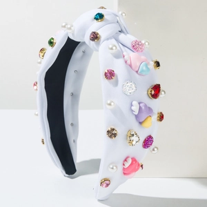 Close-up of knotted white headband with colorful rhinestones, pearls and heart charms