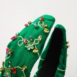 Detail of green fabric headband with gold embroidery and colorful crystal rhinestones