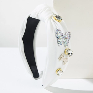 Detailed view of white padded headband featuring crystal butterfly and pearl bow ornaments