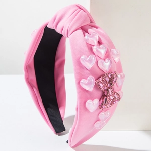 Detail of pink knitted headband with iridescent heart beads and rhinestone bow