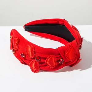 Detail view of red fabric knotted headband with heart embroidery and crystal rhinestones