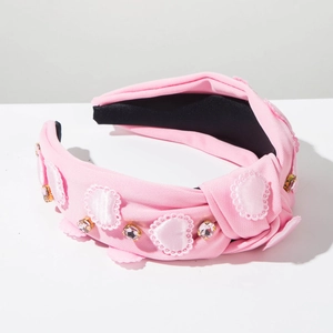 Close-up of pink fabric headband with rhinestone hearts and soft lace details