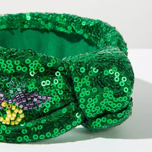 Detail of green sequin headband with colorful beaded floral accents and knotted design