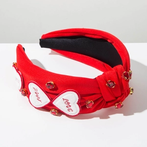 Détail d'un serre-tête rouge noué avec patchs cœurs LOVE et strass rouges brillants