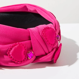 Detail of rose red knotted headband with satin hearts and sparkling pink rhinestones