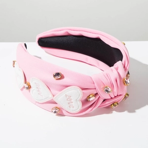 Gros plan sur un serre-tête en tissu rose avec broderie coeur et cristaux