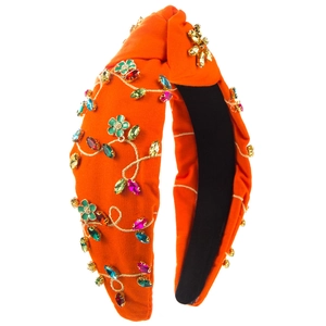 Detailed close-up of orange fabric headband with colorful rhinestones and floral embroidery