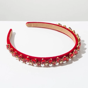 Detail view of red velvet headband with heart-shaped crystals and pearls on white background
