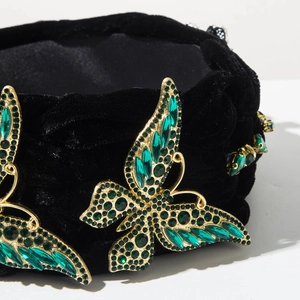 Détail de papillons en strass verts sur un serre-tête tressé en velours noir élégant