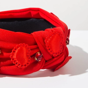 Detailed macro view of red satin headband with heart embroidery and crystal rhinestones