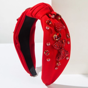 Red headband with rhinestone bow and heart charms on a white minimalist display stand