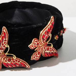 Détail du papillon en strass rouges et fleurs sur un serre-tête en velours noir