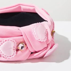 Detail of pink fabric headband with rhinestone heart embroidery and textured knit finish