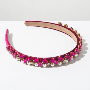 Macro detail of burgundy velvet headband featuring pink heart crystals and white pearls