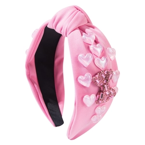 Pink fabric knot headband with shiny heart charms and sparkling rhinestone bow detail