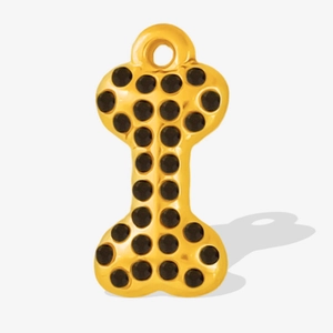 Macro shot of bone-shaped stainless steel pendant with gold finish and black crystal inlay