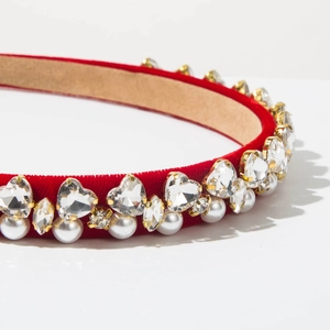 Close-up of red velvet headband with heart crystals and pearls on gold settings