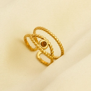 Macro shot of 3-layer beaded gold ring with amber round gemstone and open adjustable band