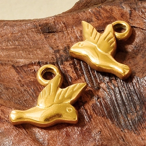 Macro view of two golden bird pendants with feather textures on a wooden background