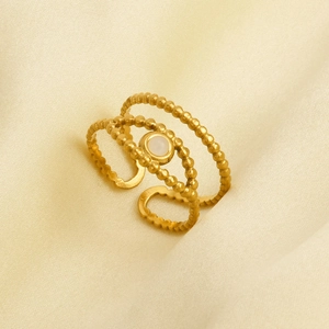 Macro view of gold 3-layer beaded ring with round white opal stone on silk background