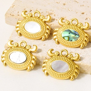 Détail de pendentifs crabe en acier inoxydable doré avec incrustations de nacre naturelle