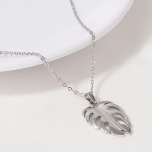 Vue détaillée d'un pendentif feuille de Monstera argenté sur une fine chaîne en métal