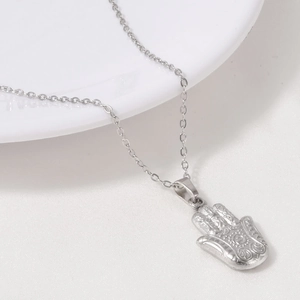 Macro shot of silver Hamsa hand pendant with embossed details on stainless steel chain
