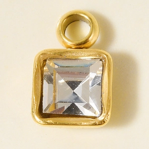 Nahaufnahme eines goldenen quadratischen Anhängers mit Glasstein und einer Metallöse