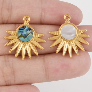 Détail de pendentifs soleil en acier doré avec incrustations de nacre et d'abalone