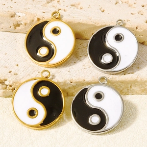Close-up of four Yin Yang pendants in gold and silver finish on stone base