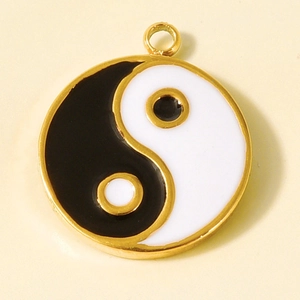 Macro detail of gold Yin Yang Tai Chi charm with black and white enamel finish