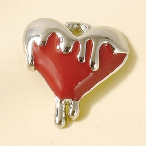 Macro detail of heart charm with liquid silver texture over red enamel finish
