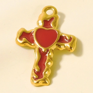 Macro shot of gold cross pendant with red enamel heart and molten metal edges