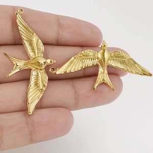 3D flying bird swallow pendants in 18k gold plated stainless steel held in hand