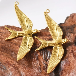 Macro detail of 18k gold swallow bird charms with feather texture on wood base