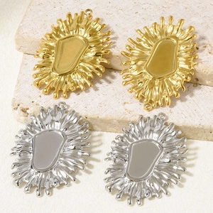 Detailed view of gold and silver irregular sunburst charms on textured stone