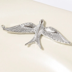 Macro detail of bird pendant showing intricate feather textures and polished steel finish