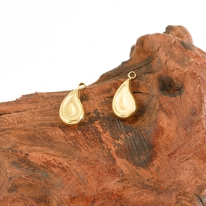 Detail of gold water drop pendants with matte texture and rings on natural wood
