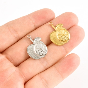 Gros plan de pendentifs fruits or et argent sur la main pour bijoux DIY