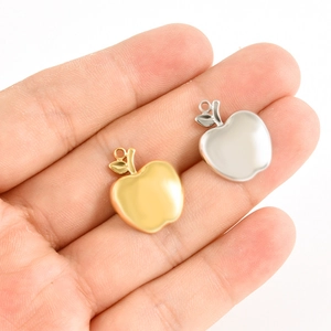 Gros plan de pendentifs en forme de pomme or et argent pour la création de bijoux