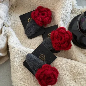 Handmade red crochet rose hair clips on display card with soft beige fabric background