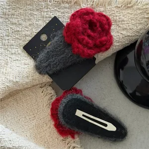 Detailed view of red knitted flower hair clips with grey wool pads and BB clip backing