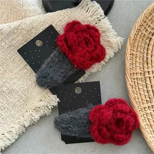 Handmade red crochet flower hair clips on display card with gray stone background