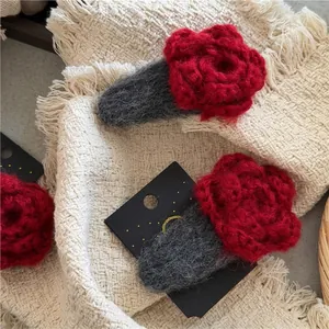 Handmade red crochet rose hair clips with knitted grey base on elegant fabric background